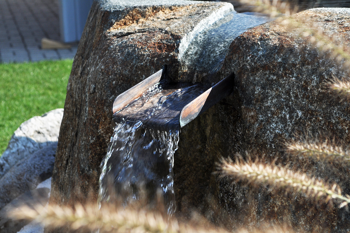 Ein Wasserlauf im sommerlichen Garten, das Wasser plätschert dahin.